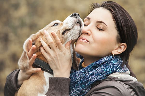 woman nuzzling a dog's face